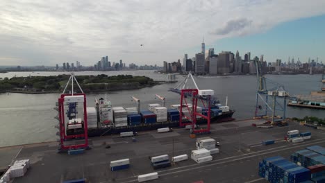 container ships being loaded in new york harbor, industrial scene with manhattan skyline in distance, 4k aerial