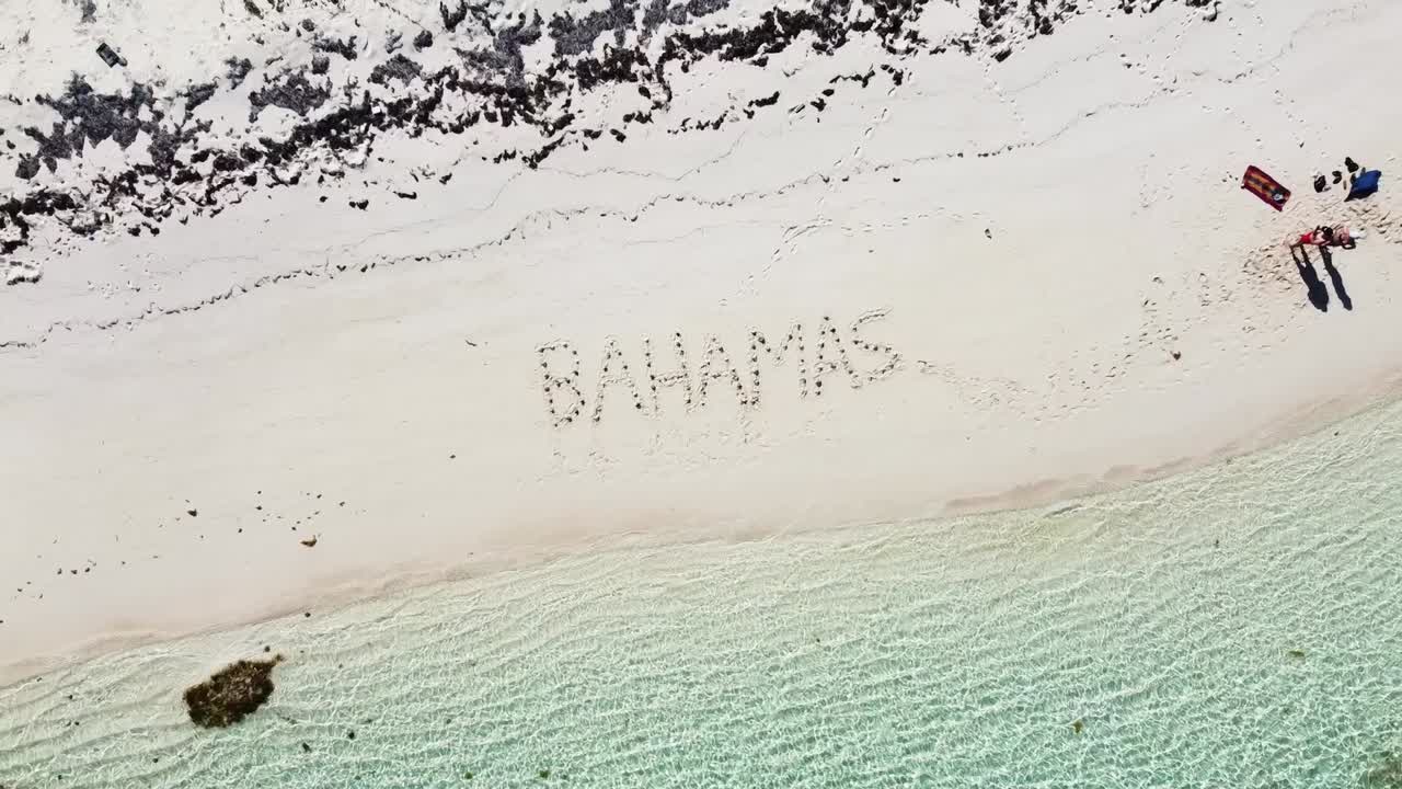 한 커플이 조개껍데기로 해변에 "bahamas"라고 썼다
