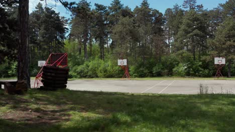 empty basketball courts in outdoor forest setting, sliding aerial view