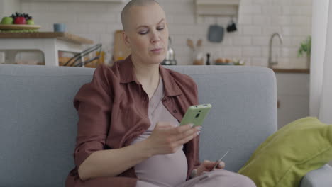 pregnant woman using phone and credit card at home