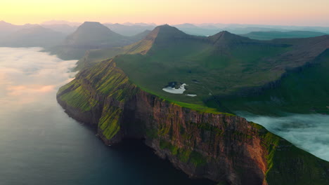 aerial view of majestic green coastal mountains and fog at sunrise
