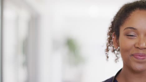 Half-face-video-portrait-of-happy-biracial-female-doctor-smiling-in-hospital,-with-copy-space