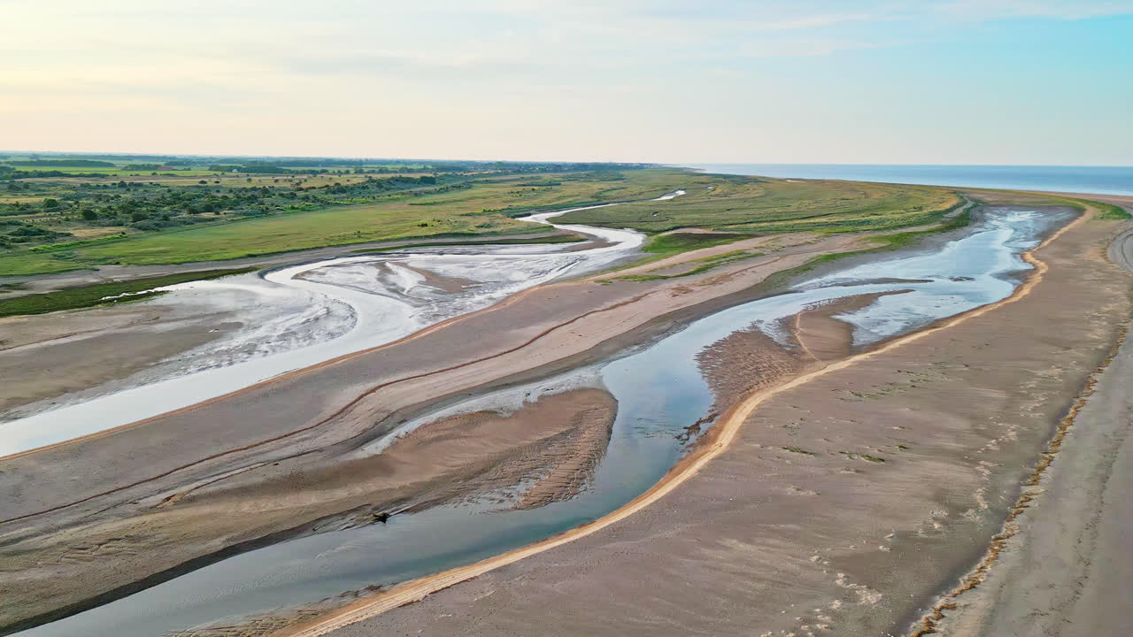 Découvrez le charme idyllique d'une scène côtière à l'heure dorée grâce à des images aériennes à couper le souffle prises par drone : estuaire, bancs de sable, océan et marais