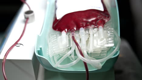 bubbles of air move back and forth in the plastic bag filled with blood. medical machine is waving the bag. close up.