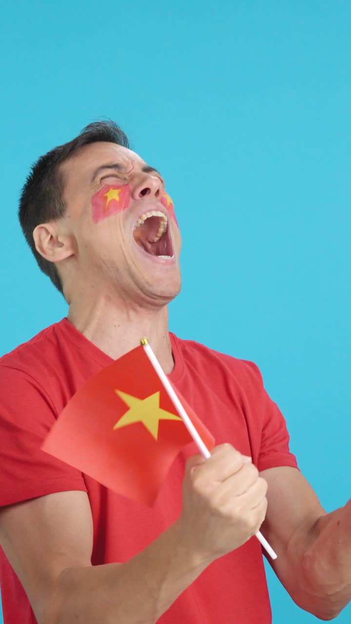 Man cheering for Vietnam waving a national flag looking away