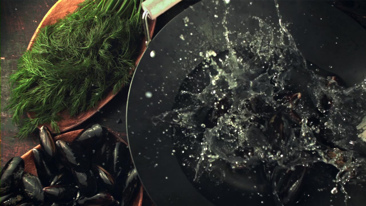 Cozze fresche che schizzano nell'acqua in una padella con aneto