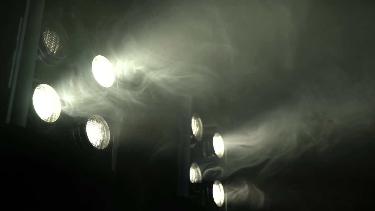 Eight spotlights flicker in a smoky room
