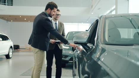 car salesman discussing a car with a customer in a dealership