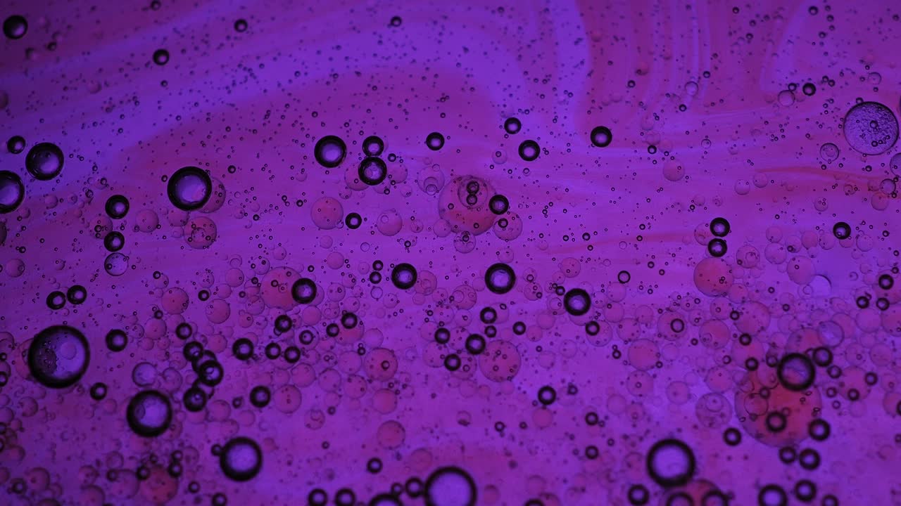 Mixing water and oil, beautiful colors. Purple light. Abstract macro background. Water and oil bubbles. Abstract light illumination