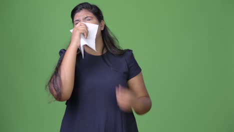 young overweight beautiful indian businesswoman against green background