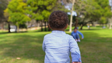 Niño-Corriendo-Hacia-La-Madre-Tirada-En-El-Pasto,-Madre-Huyendo