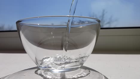 water is poured into empty glasses on a sunny windowsill.