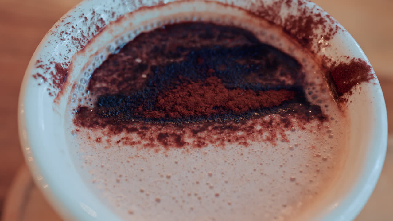 Primo piano di una ricca superficie di cioccolata calda o caffè cosparsa di cacao in polvere