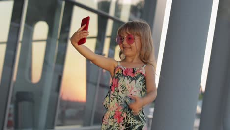 Tourist-kid-girl-wearing-trendy-sunglasses-use-phone.-Child-using-smartphone-for-video-call,-selfie