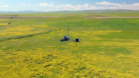 Old-windmill-in-the-field-of-yellow-flowers,-aerial-shot