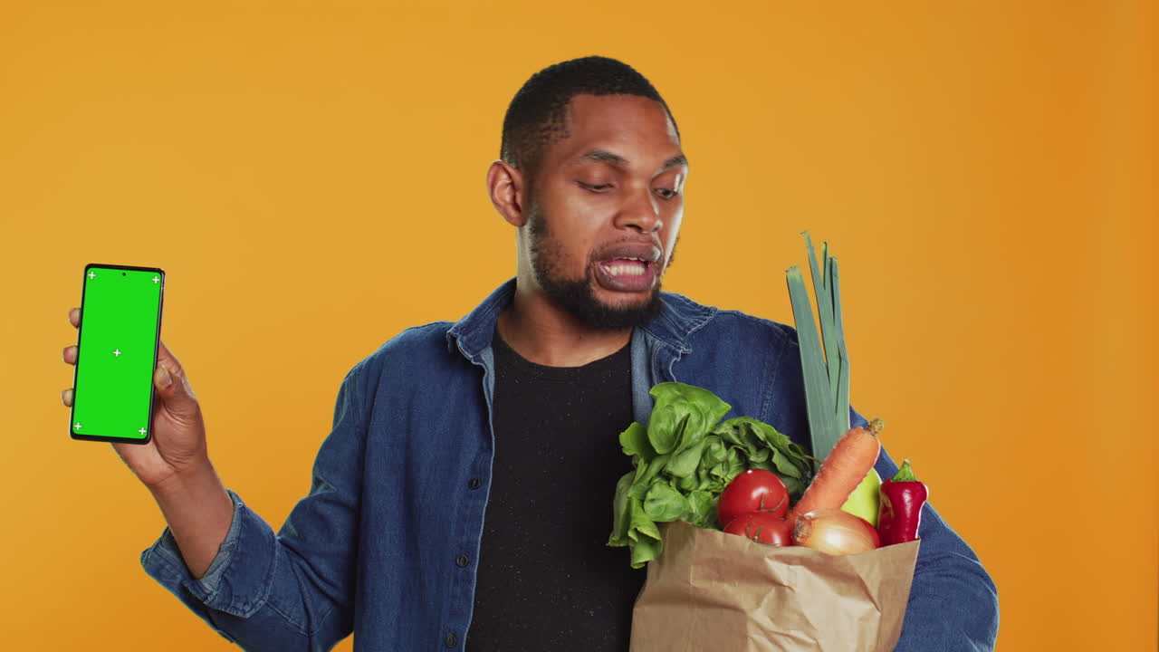 hombre afroamericano mostrando un teléfono con una pantalla de maqueta aislada