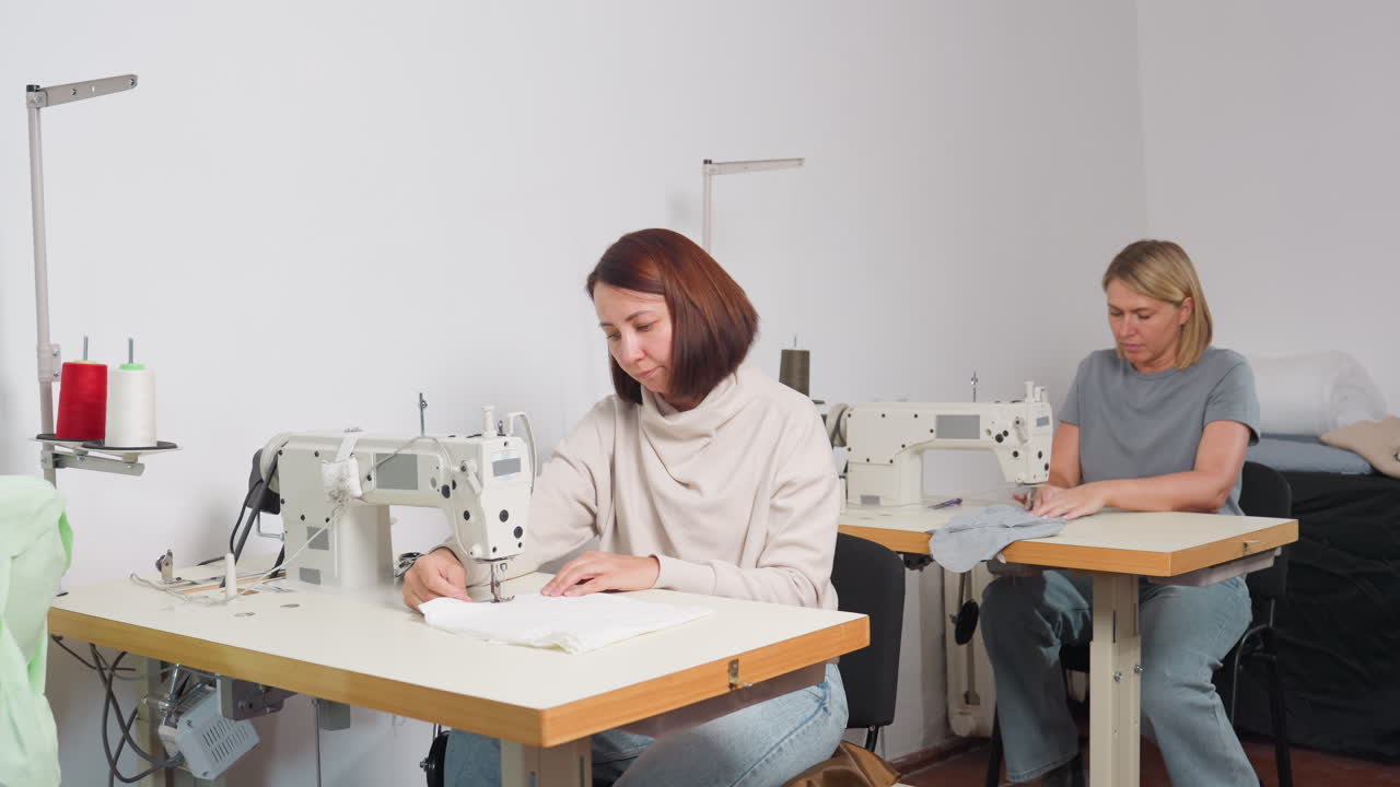 Wide view of clothing designers focused on sewing piece of fabric ...