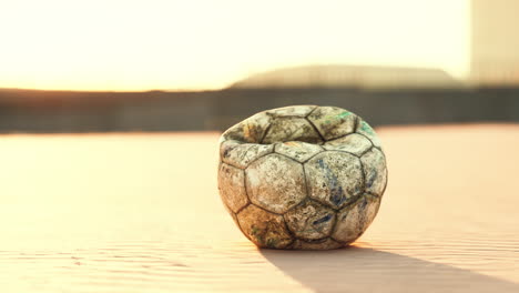 old dirty soccer ball on a field at sunset