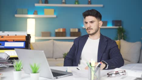 trabajador de oficina en casa mirando la computadora portátil y enojándose.