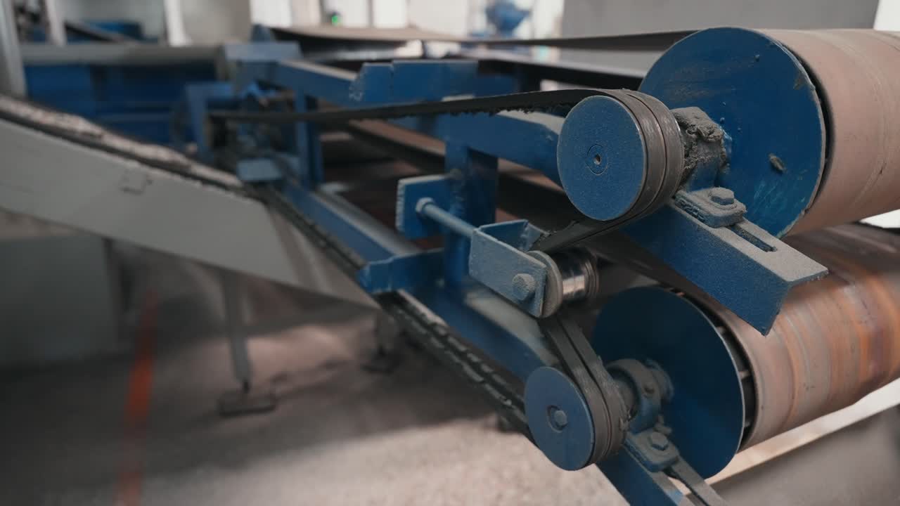 Close up mechanical conveyor belt system moving materials inside rubber recycling factory
