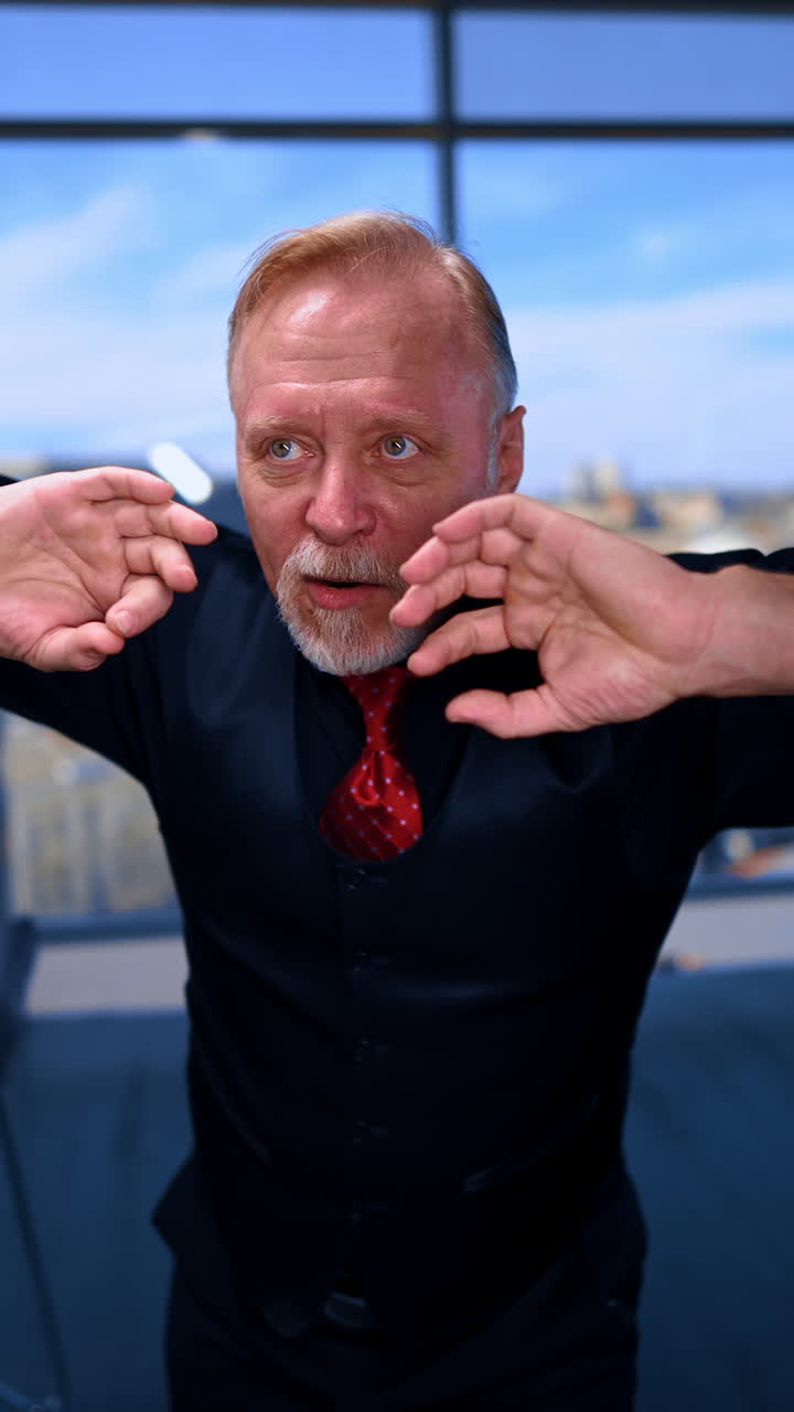 Adult male wearing a shirt with tie and vest stands in front of camera. Mature man having fun, making faces. Close up. Vertical video.