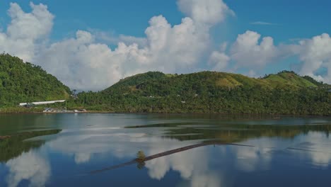 una paralaje cinematográfica de estanques de peces en surigao, filipinas, utilizado para atrapar camarones pasayan, rodeado de colinas exuberantes y cielo azul