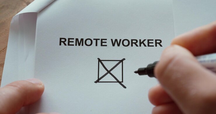Close-up of a person using a black marker to check a checkbox labeled Remote Worker on a printed paper. Concept of remote work, working from home, flexible employment, telecommuting and modern workpla