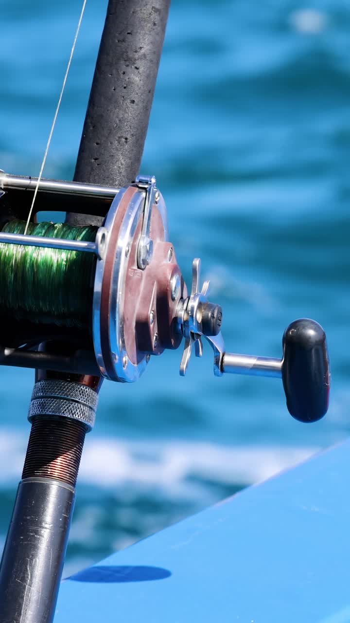Una canna da pesca su una barca a Phuket, Thailandia, cattura l'essenza di una serena battuta di pesca con vivaci onde oceaniche.