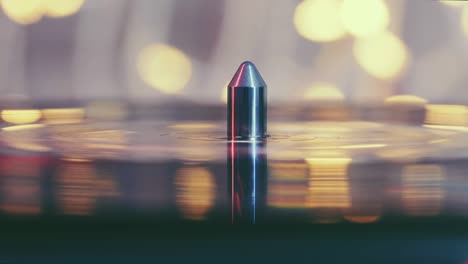 fragment of a rotating black vinyl record player turntable on a pale pink background with blurry bright lights. turntable vinyl record player to listen to