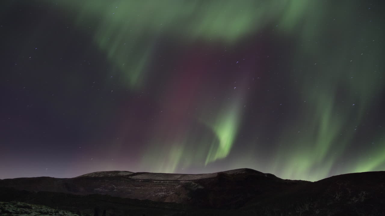 un bucle continuo de luces del norte en cascada sobre las montañas en el cielo estrellado