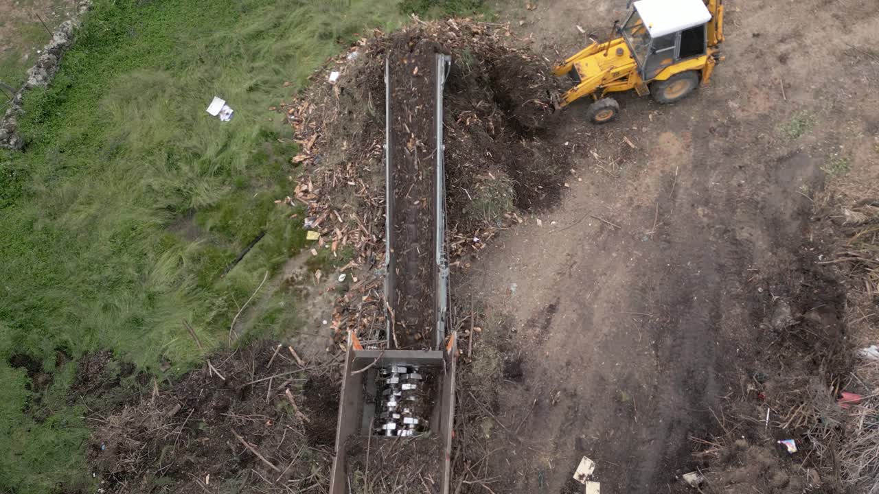 Volo di drone dove vediamo in una ripresa aerea il lavoro svolto da un trituratore con i resti della potatura degli alberi