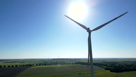 Close-up-of-wind-turbine-blades-rotating-against-the-backdrop-of-the-full-sun,-renewable-energy-sources