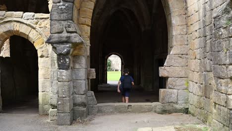 young boy walking through a medieval archway at fountains abbey ruins in yorkshire uk