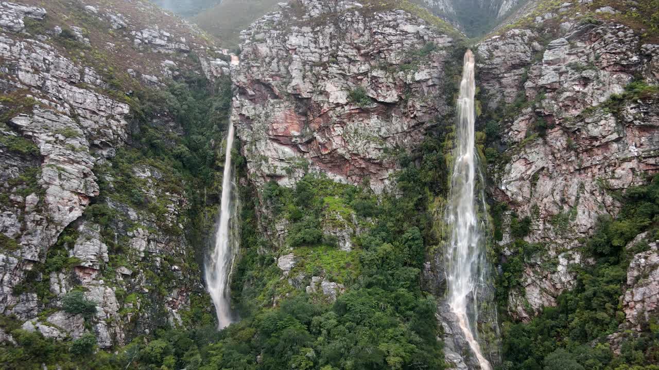 varias cascadas que fluyen por un lado de la montaña con acantilados y una atmósfera nublada y lluviosa de mal humor