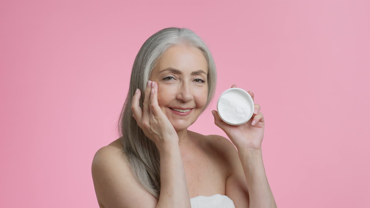 mujer mayor aplicando crema facial