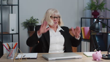 Irritated-senior-business-woman-hits-table-with-fist,-closes-broken-laggy-buggy-laptop-computer