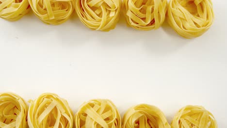 parallels roll of tagliatelle pasta on the edge on white background