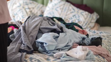 messy bedroom with pile of clothes on bed
