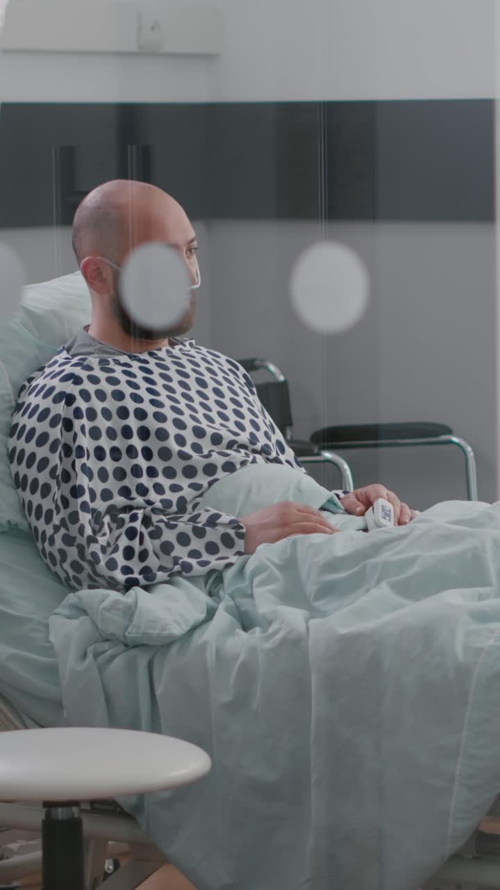 Video verticale: uomo malato e stressato seduto a letto in attesa di cure respiratorie