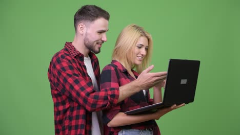 young happy couple smiling while using laptop together