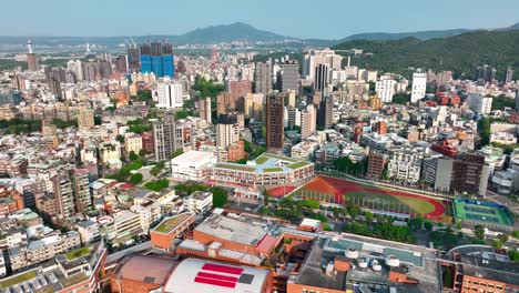 Aerial-panoramic-shot-of-Taipei-Cityscape-with-Football-field-and-bali-mountain-in-background,-Taiwan