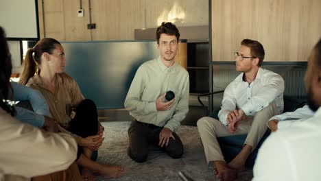 a man in a shirt gives his opinion at a group therapy for people in the office