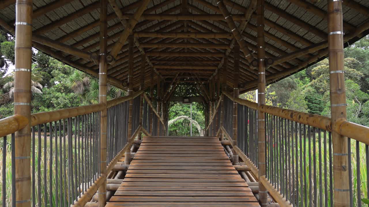 Symmetrical view of bamboo bridge at Bogotá Botanical Garden, framed by greenery and guadua design