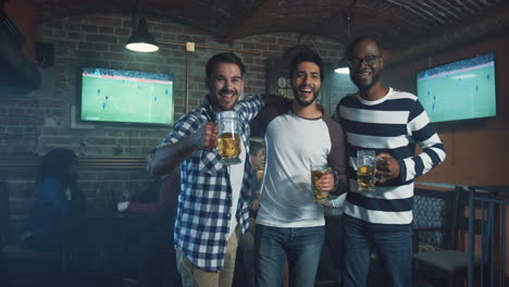 three multiethnic smiled men standing and posing to the camera with beer in hands