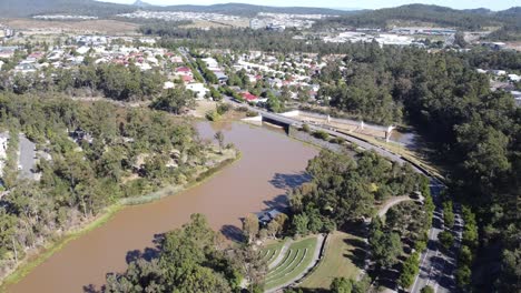 Vista-Aérea-De-Un-Suburbio-Australiano-Cerca-De-Un-Lago-Artificial-Con-Un-Puente-Sobre-El-Aliviadero