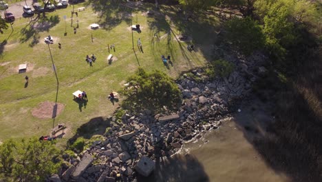 people relaxing in the sun on green meadow along river shore