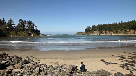 People-on-beach-and-paddle-boarder-at-Sunset-Bay-State-Park,-Oregon