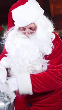 happy female elf looking at santa pouring water. preparation for drinking tea with cookies on christmas background. vertical video