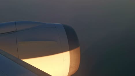 warm sunlight hitting the engine of a plane that flies over a foggy sky