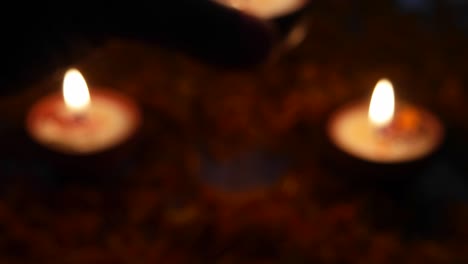 extreme close up of a man holding a diya, focus shift and he places it with other diyas or lamps lit up for diwali 'festival of light', the most important ancient hindu festival celebrated